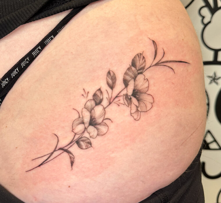 fine-line delicate vine tattoo with blossoms